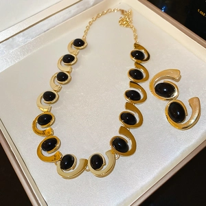 Detailed view of a gold jewelry set with oval black stones in a white silk-lined box
