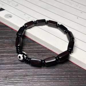 Ethnic ebony wood bracelet with rectangular beads and patterned Dzi bead on vintage book