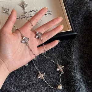 Gros plan d'un collier vintage argenté avec pendentifs croix oeil de tigre et perles