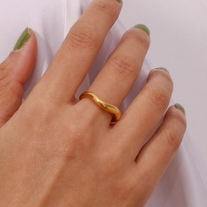 Minimalist 18K gold plated stainless steel wave ring worn on finger with glossy finish