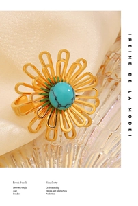 Primo piano di un anello a fiore dorato con turchese su elegante sfondo di seta