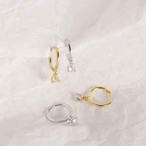 Close-up of gold and silver mini hoop earrings with sparkling round zircon charms