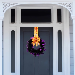 Detail of Halloween wreath with purple tinsel, bats and orange pumpkin ribbon on front door