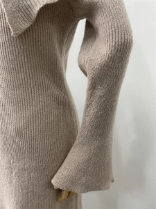 Close-up detail of knitted oatmeal off-shoulder dress showing fine texture and sleek cuffs