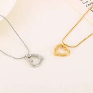 Close-up of gold and silver heart-shaped hollow pendants on thin snake bone chains