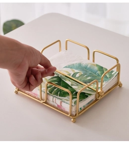 Close-up of golden iron napkin holder with small round feet on a white table surface