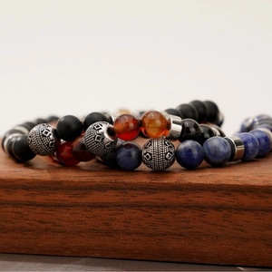 Men's natural stone bead bracelets with black agate and blue sodalite on wood