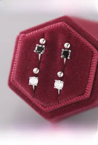 Detailed macro view of four-prong silver stud earrings in a luxury red velvet gift box