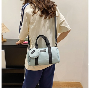 Detail of light blue nylon Boston bag featuring a round coin purse and black straps
