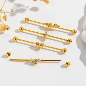 Set of 4 gold industrial piercing barbells with snake, cross, and heart rhinestone charms