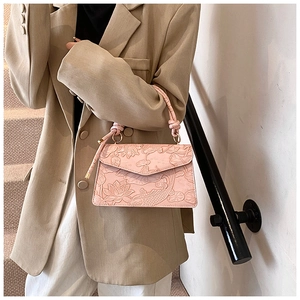 Close-up of pink handbag with embossed lotus and koi fish patterns on textured leather