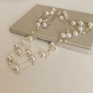French vintage style multi-layer pearl necklace with gold chains on art book background