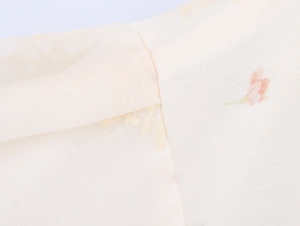 Gros plan d'une broderie florale sur tissu de coton crème avec coutures et texture fine