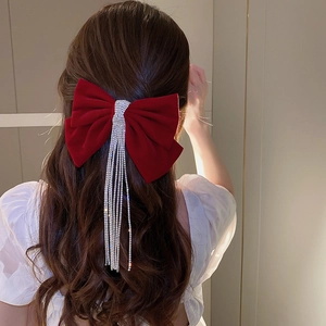 Close-up of red velvet bow hair clip with long sparkling rhinestone tassels on hair