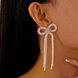 Détail de boucles d'oreilles nœud argentées avec cristaux et pampilles mobiles