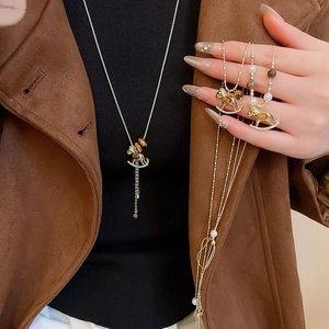 Detail of a gold rocking horse pendant with tiger eye stone and pearls on a model