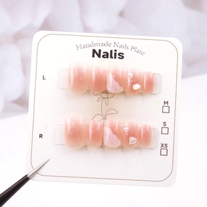 Detail of pink gradient handmade nails with glitter, pearls and shell fragments