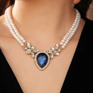 Gros plan du collier de perles à double rangée avec pendentif en pierre bleue sur un mannequin