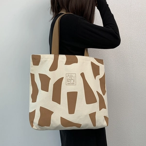 Detail of canvas tote bag with brown geometric patterns and cartoon rabbit illustration