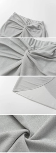 Detail of silver metallic swimsuit showing elastic waist, knot design and shimmering fabric