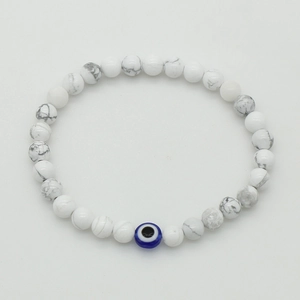 Close-up of white turquoise beaded bracelet with blue evil eye charm on elastic cord