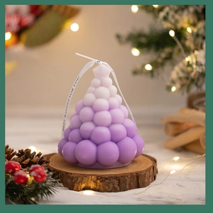 Macro detail of a purple gradient Christmas tree candle with a ribbon on a wooden tray