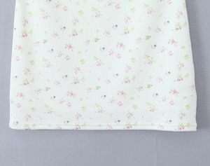 Détail de l'ourlet en tricot côtelé avec un imprimé floral délicat sur un tissu blanc