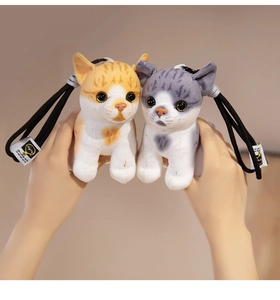 Close-up of adorable orange and grey striped plush cat keychains held in hands