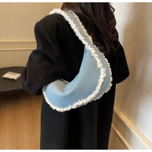 Close-up of light blue crescent underarm bag featuring white frayed tassel edge detail