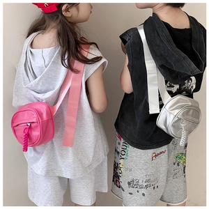 Detail view of pink and silver shiny round crossbody bags for kids on stylish outfits