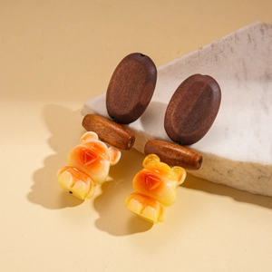 Detail of bohemian bear earrings featuring carved resin and geometric wood elements