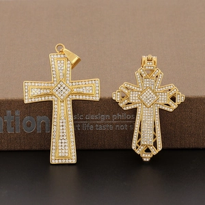 Détail de deux pendentifs croix hip hop dorés avec zircons et design ajouré élégant