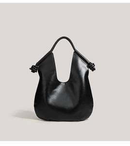 Detail of a black leather hobo bag featuring stylish knot accents on the shoulder strap