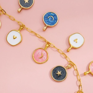 Detailed macro view of gold chain charms with colorful enamel moon, star, and heart patterns