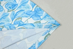 Detail of blue and white floral print fabric with precise overlock stitching on the hem