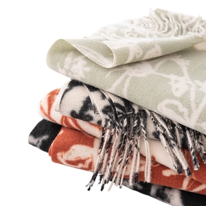 Stack of patterned cashmere-like scarves in green, beige, and orange with elegant tassels