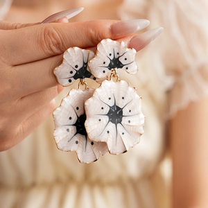 Détail de boucles d'oreilles vintage feuille de ginkgo émaillées blanc et doré
