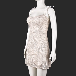 Détail de paillettes argentées sur une mini robe dos nu beige à fines bretelles