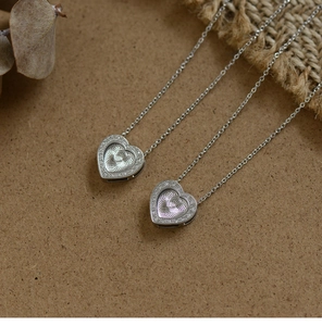 Macro shot of silver heart pendants with radial texture and zircon accents on brown surface