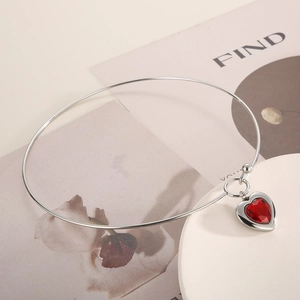 Detail of elegant silver choker necklace featuring a faceted red glass heart pendant