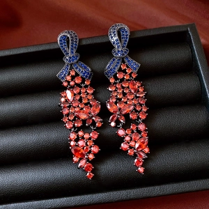 Détail de boucles d'oreilles vintage avec nœud en diamants bleus et pendentif gemme rouge