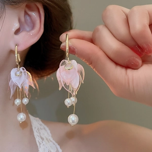 Detail of pink acrylic flower earrings with pearl tassels and gold-plated hooks
