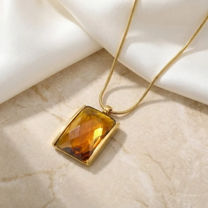 Detail of amber glass square pendant on 18K gold plated snake chain over silk