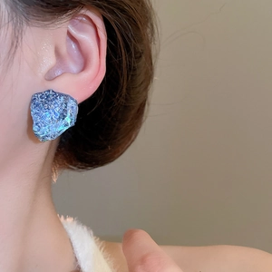 Close-up of model wearing blue irregular resin stud earrings with mineral texture