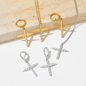Close-up of gold and silver cross wings jewelry set with sparkling pavé crystals