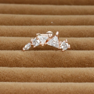 Détail macro du piercing d'oreille or rose avec zircons géométriques incurvés