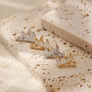 Macro shot of crown stud earrings in gold and silver finish with sparkling zircons