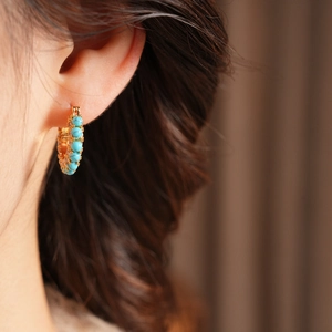 Close-up of elegant 18k gold plated hoop earrings featuring vintage turquoise beads