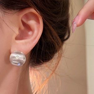 Brushed silver hemispherical stud earrings with zircon accents on a model