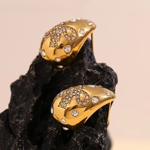 Detailed close-up of luxurious 18K gold-plated teardrop butterfly earrings on black stone